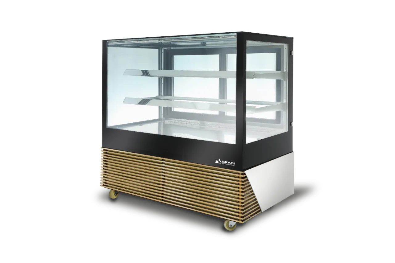 A sleek, modern cake display cabinet with a glass front and two glass shelves. The base features a stylish wood-like paneling with ventilation slats and wheels for mobility. Product branding "SKADI" is visible in the lower corner, showcasing the [High-Efficiency Commercial Cake Display Cabinet | TLR-D].