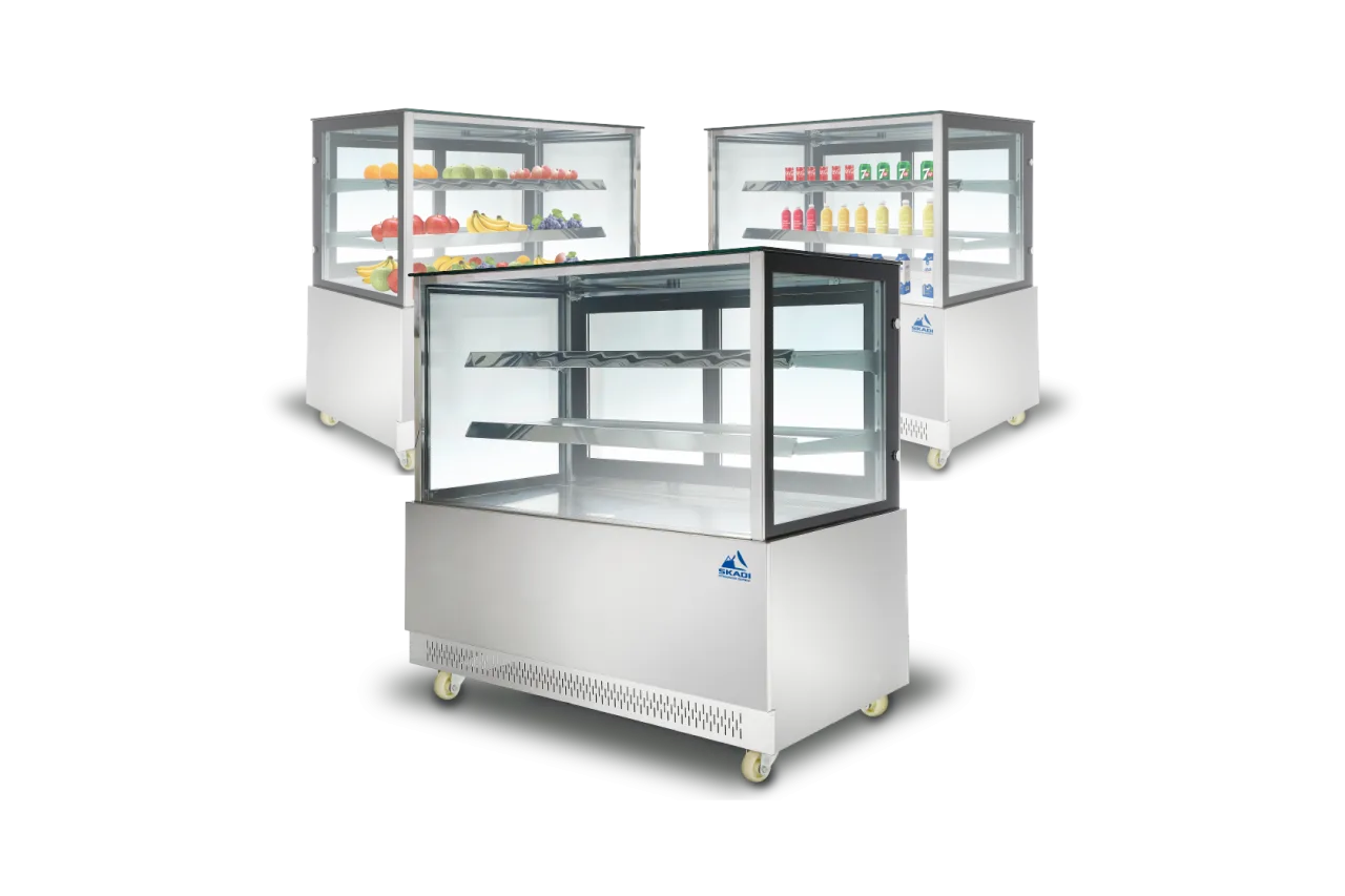 Three Wide Body Commercial Cake Display Cabinets | PNR-D are shown in use. One is filled with fresh fruits, another with beverages, and a third is displayed empty, showcasing the cabinet’s versatile shelving and clear glass design.