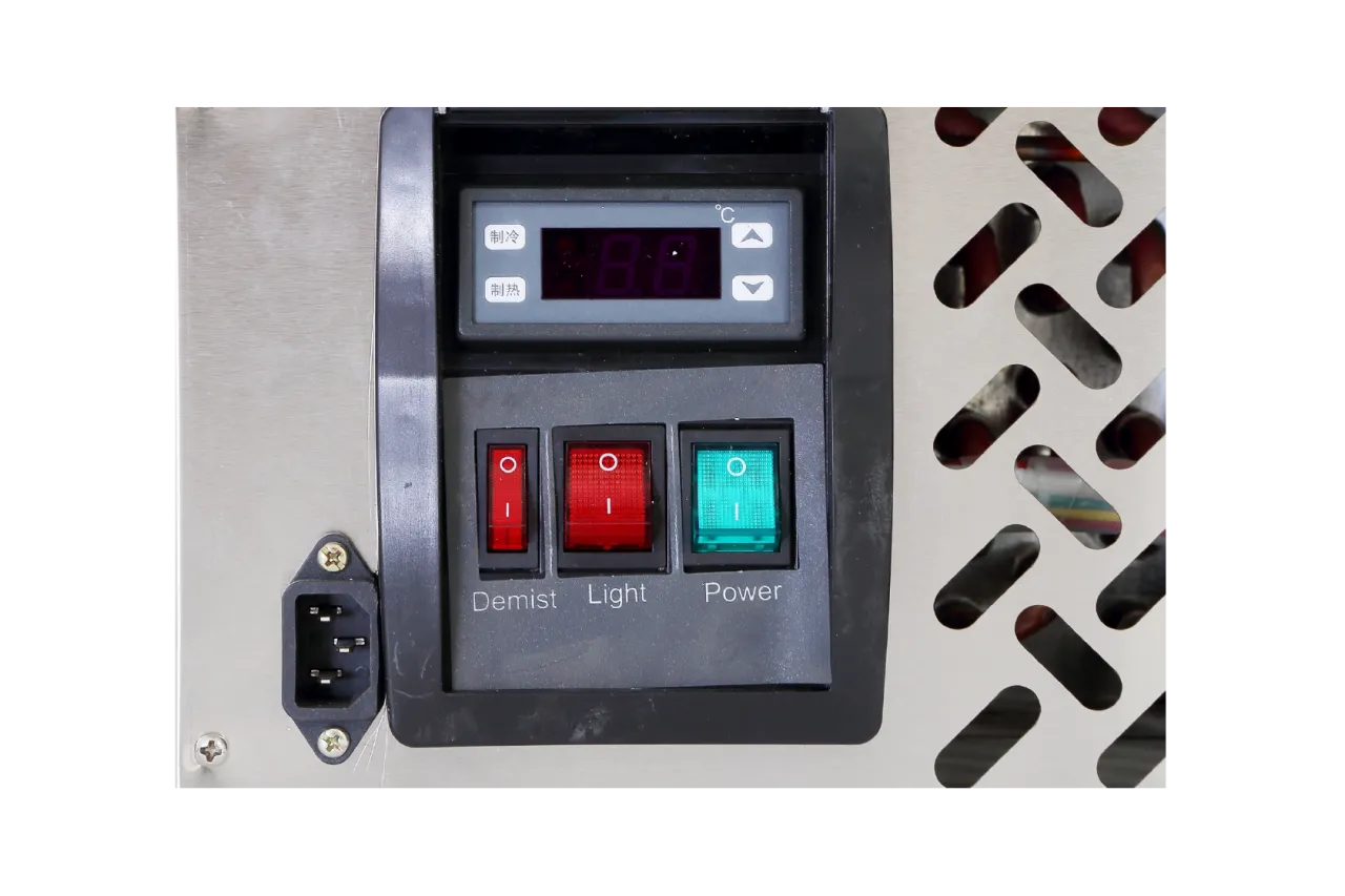 Close-up of the control panel of the Spacious Countertop Cake Display Cabinet | CTR featuring three switches labeled Demist, Light, and Power. The Demist and Light switches are red, while the Power switch is green, with a digital temperature display above them.