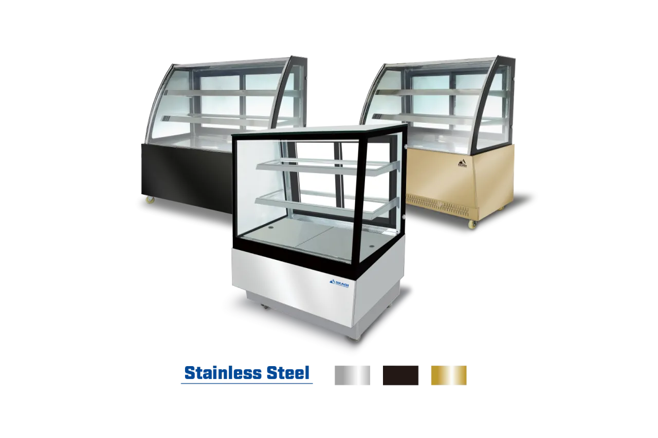 Three variations of the Compact Cake Display Showcase with Right-Angle Design | ORX-D, shown in stainless steel, black, and gold finishes. The units have a sleek, modern design with two internal shelves for displaying cakes and pastries.